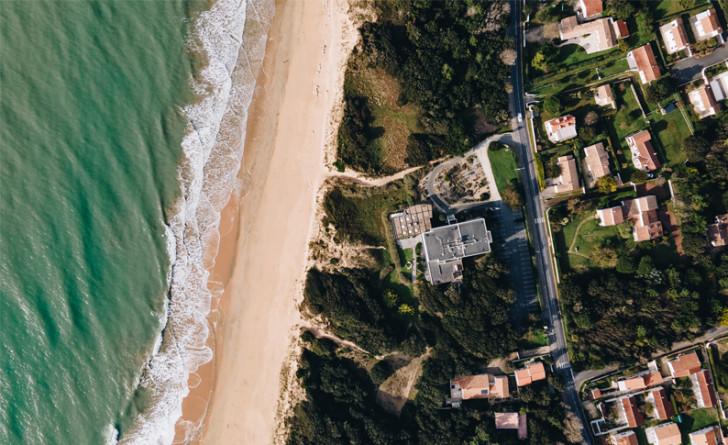 Vue du ciel d'un bord de mer avec des habitations sur la droite de l'image